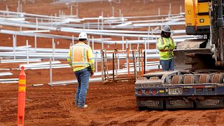 Construction crews work on unfinished racks for solar panels at the AES Corporation's West Oahu solar farm in Kapolei, Hawai'i.
