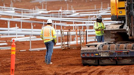 Construction crews work on unfinished racks for solar panels at the AES Corporation's West Oahu solar farm in Kapolei, Hawai'i.