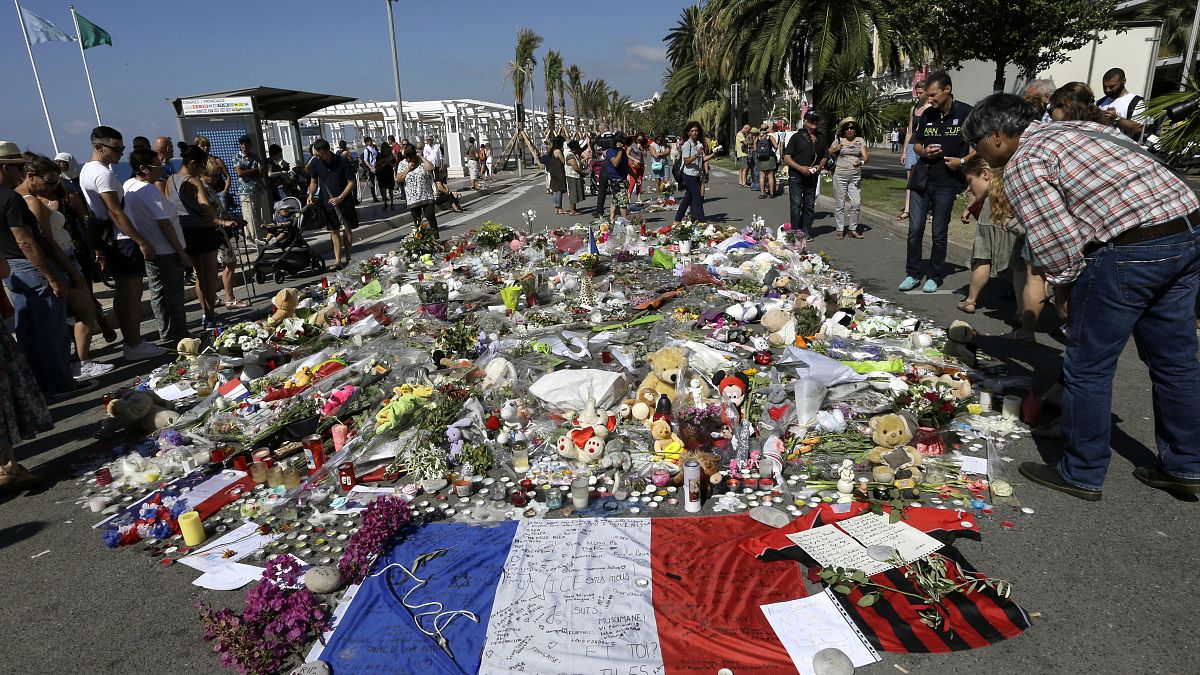 La gente mira las flores colocadas en el Paseo de los Ingleses en el lugar del atentado con un camión