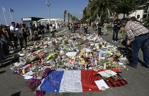 La gente mira las flores colocadas en el Paseo de los Ingleses en el lugar del atentado con un camión