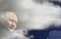 Russian President Vladimir Putin seen through a bus window, which reflects sky and clouds, during his visit to Kaliningrad in July 2005