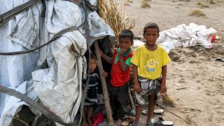 أطفال يمينيون يقفون خارج خيمة في مخيم للنازحين دمرته الأمطار الغزيرة في منطقة الجراحي بمحافظة الحديدة غربي البلاد التي دمرتها الحرب في 19 أغسطس 2022.