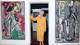 Peggy Guggenheim poses between early paintings by Jackson Pollock that are part of her modern art collection at her 18th century palace, Palazzo Venier dei Leoni, in Venice