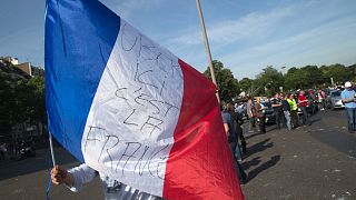 A taxi driver waves a French flag with inscription reading "Uber, here it's France" during a demonstration in Paris, Thursday, June 25, 2015 in Paris.