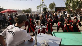 زائر يشاهد عرض راقصين فلسطينيين خلال مهرجان أكتوبر السنوي للبيرة في قرية طيبة في الضفة الغربية المحتلة. 2022/09/02