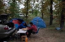 Two men play backgammon as they sit next to camping tents in an area on the road side of a village about 30 kilometers from the Zaporizhzhia nuclear plant.