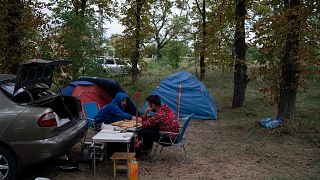 Two men play backgammon as they sit next to camping tents in an area on the road side of a village about 30 kilometers from the Zaporizhzhia nuclear plant. 