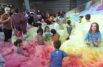 Attendees at an art insulation in London play in an island of foam.