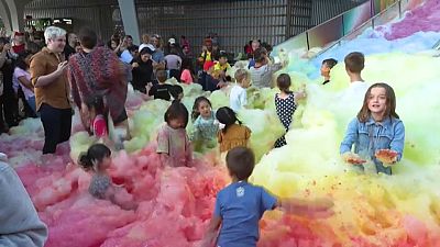 Attendees at an art insulation in London play in an island of foam. 