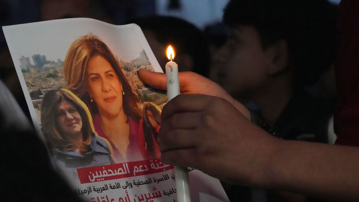 فلسطيني يحمل صورة الصحفية الفلسطينية الأمريكية شيرين أبو عاقلة خلال تكريم بالشموع للتنديد بمقتلها في مدينة غزة - 11 مايو- أيار 2022.
