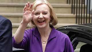 Η νέα πρωθυπουργός της Βρετανίας Λιζ Τρας χαιρετάει χαμογελαστή τους δημοσιογράφους ενώ φτάνει στα γραφεία του Συντηρητικού κόμματος στο Λονδίνο