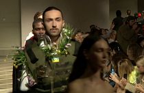 Model donning Bulletproof vest with flowers poking out 