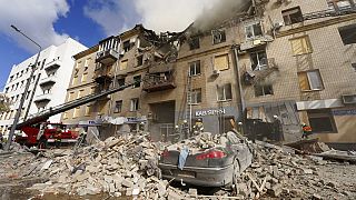 Ukrainian firefighters work on heavily damaged buildings
