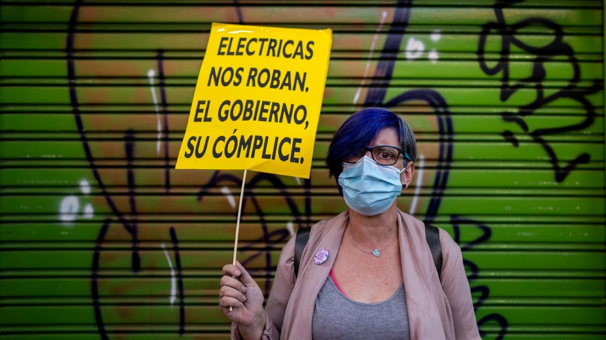 A woman holds a sign reading "The electric companies rob us. The government their accomplice" as she protests the rise in electricity prices in Madrid, Spain, Oct. 6, 2021.