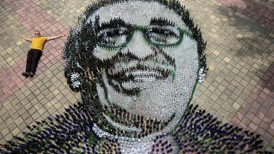 Aerial view showing artist Eduardo Butron posing with recycled glass bottles forming the image of Colombian writer Gabriel Garcia Marquez.