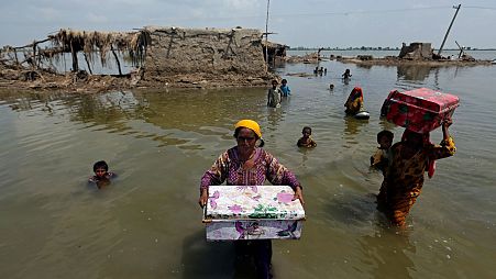 Women carry belongings salvaged from their flooded home after monsoon rains, in the Qambar Shahdadkot district of Sindh Province, of Pakistan.