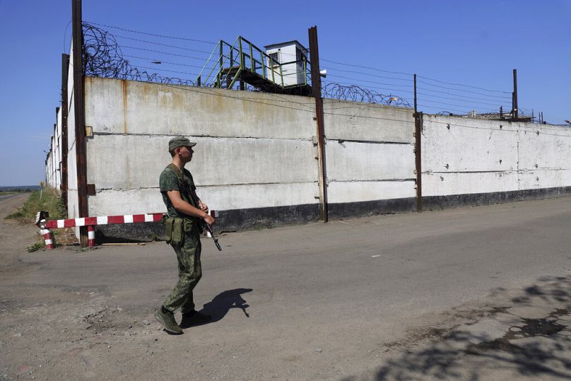 Un soldat monte la garde près du mur d'une prison à Olenivka, dans une zone contrôlée par les forces séparatistes soutenues par la Russie, dans l'est de l'Ukraine, 29.07.2022