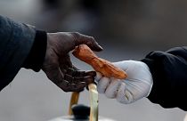 A woman working for a social organization hands a snack to a homeless man on 9 de Julio Avenue in Buenos Aires, Argentina, Monday, May 31, 2021