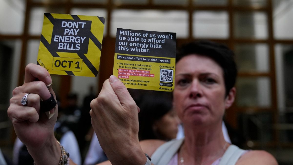 A demonstrator holds up two cards as they protest outside the British energy regulator Ofgem