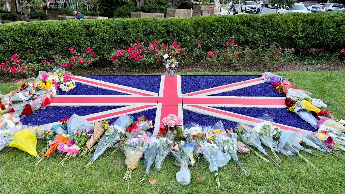 Bandera rodeada de ramos de glores en señal de luto por la muerte de la reina Isabel II