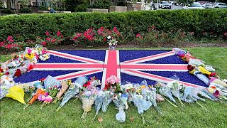 Bandera rodeada de ramos de glores en señal de luto por la muerte de la reina Isabel II