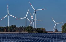 Wind turbines turn behind a solar farm in Rapshagen, Germany, Oct. 28, 2021.