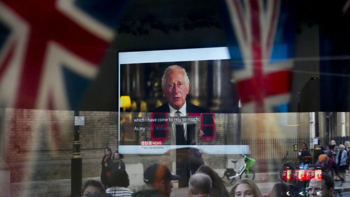 Des passants tentent d'apercevoir le discours télévisé du nouveau roi Charles III alors qu'ils passent devant un pub à Londres, vendredi 9 septembre 2022