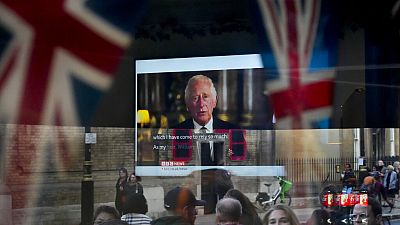 Des passants tentent d'apercevoir le discours télévisé du nouveau roi Charles III alors qu'ils passent devant un pub à Londres, vendredi 9 septembre 2022