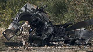 A Ukrainian soldier passes by a Russian tank damaged in a battle in a just freed territory on the road to Balakleya in the Kharkiv region, 11 September 2022