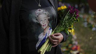 Une femme tient des fleurs au mémorial de Green Park, près du palais de Buckingham à Londres, dimanche 11 septembre 2022.