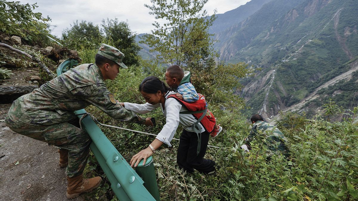 Kínai katona segít egy fiatal nőnek és gyerekének