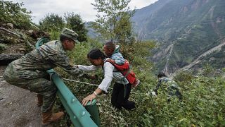 Kínai katona segít egy fiatal nőnek és gyerekének