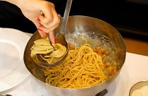 A woman spoons onto a plate some "spaghetti alla Carbonara" during a cooking competition on the eve of the Carbonara Day