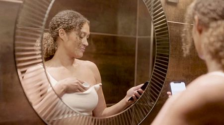 Image shows a woman using the Dotplot , a new device for women to perform at-home checks for breast cancer.