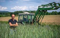 Ulf Allhoff-Cramer, farmer, stands in a rye field in front of his tractor in Detmold, Germany.