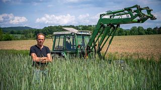 Ulf Allhoff-Cramer, farmer, stands in a rye field in front of his tractor in Detmold, Germany.