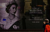 سائح يلتقط صورة على شاشة عرض تخليدا لذكرى الملكة إليزابيث الثانية، في ميدان بيكاديلي بلندن، الأحد 11 سبتمبر 2022