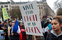 A woman holds a placard reading "Living is right, not a choice" during a demonstration against abortion and euthanasia in Paris