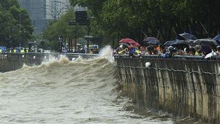 A hullámokat figyelik Hangcsouban az emberek a Muifa tájfun érkezése előtt 2022. szeptember 14-én