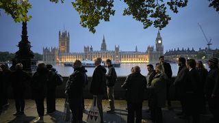 A ravatalhoz sorban állók egy csoportja, háttérben a Big Bennel és a londoni Parlament épületével