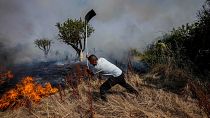 A local resident fights a forest fire with a shovel during a wildfire in Tabara, north-west Spain, July 19, 2022