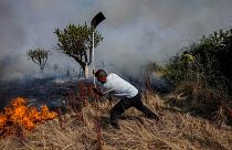 A local resident fights a forest fire with a shovel during a wildfire in Tabara, north-west Spain, July 19, 2022