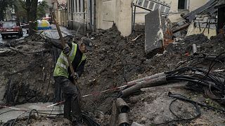 A man works next to a crater created by an explosion to fix the internet cables after a Russian attack in downtown, Kharkiv, Ukraine, Friday, 16 September 2022.
