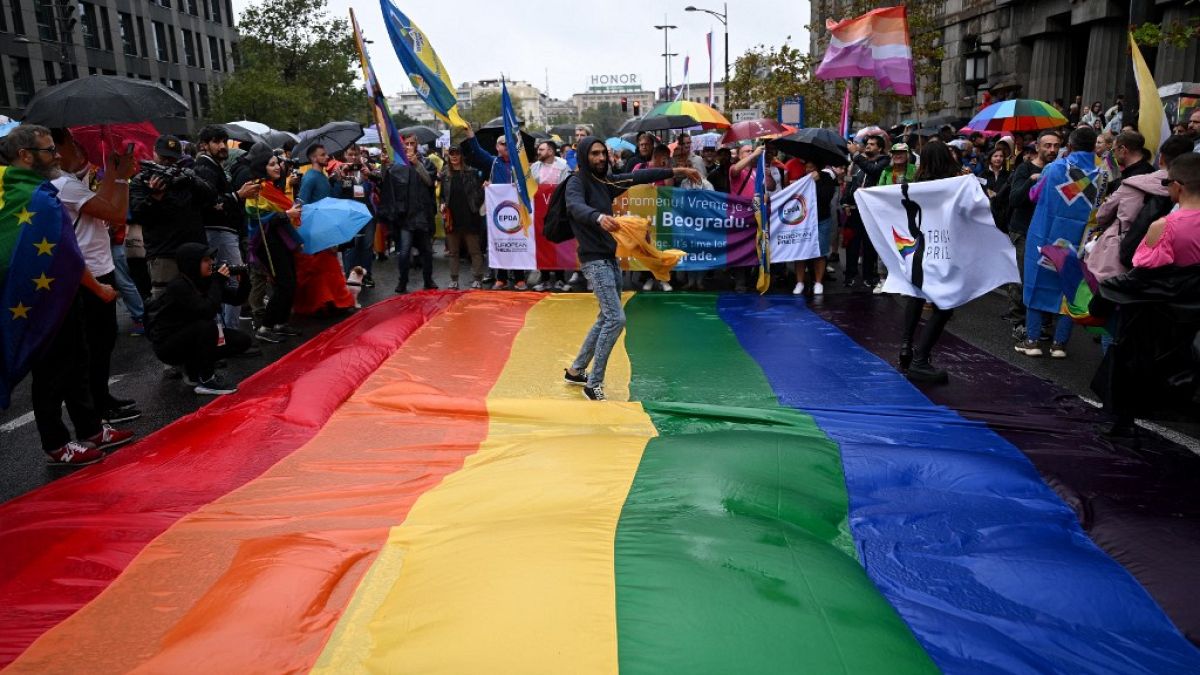 Participants dance on large rainbow flag in Belgrade as they take part in the annual LGBT+ pride march in Belgrade, Serbia, Saturday, Sept. 18, 2021. 