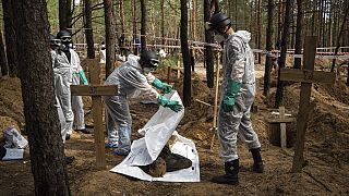 Работники МЧС закрывают полиэтиленовый пакет с телом мирного жителя во время эксгумации под Изюмом, 17.09.2022