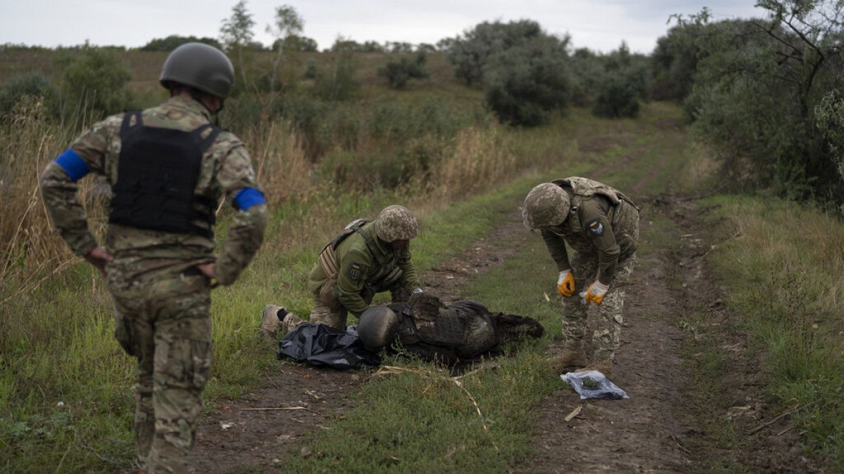 Украинские военнослужащие осматривают тело украинского солдата на отвоеванном участке у границы с Россией в Харьковской области, 17.09.2022