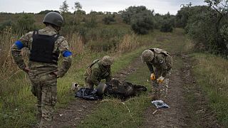 Украинские военнослужащие осматривают тело украинского солдата на отвоеванном участке у границы с Россией в Харьковской области, 17.09.2022