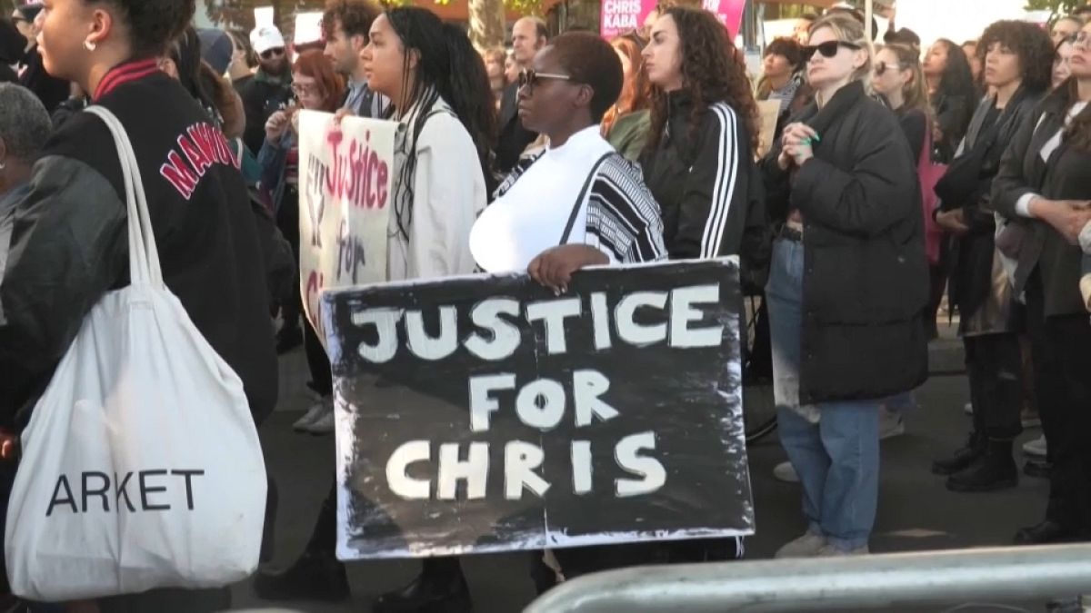 A woman holds a 'Justice for Chris' poster at a protest in London