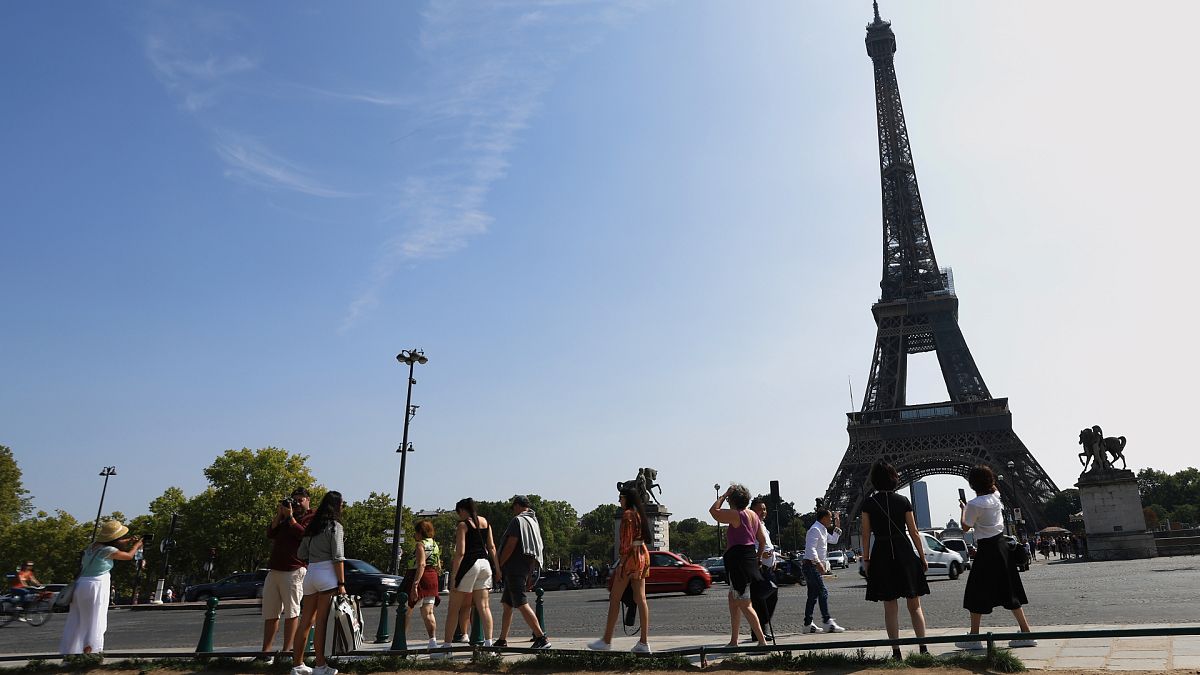Des touristes se dirigent vers la Tour Eiffel, mercredi 31 août 2022 à Paris. 
