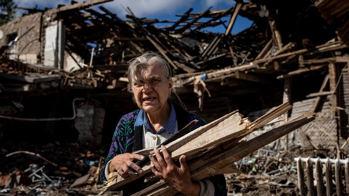 A woman collects wood for heating from a destroyed school where Russian forces were based in the recently retaken area of Izium, Ukraine, Monday, Sept. 19, 2022